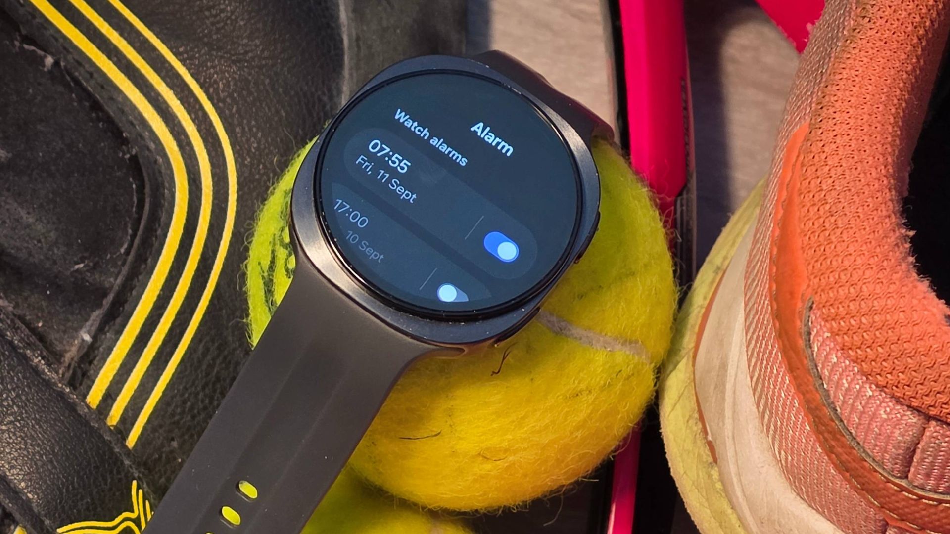 The Samsung Galaxy Watch 9 on a tennis ball, showing an alarm.