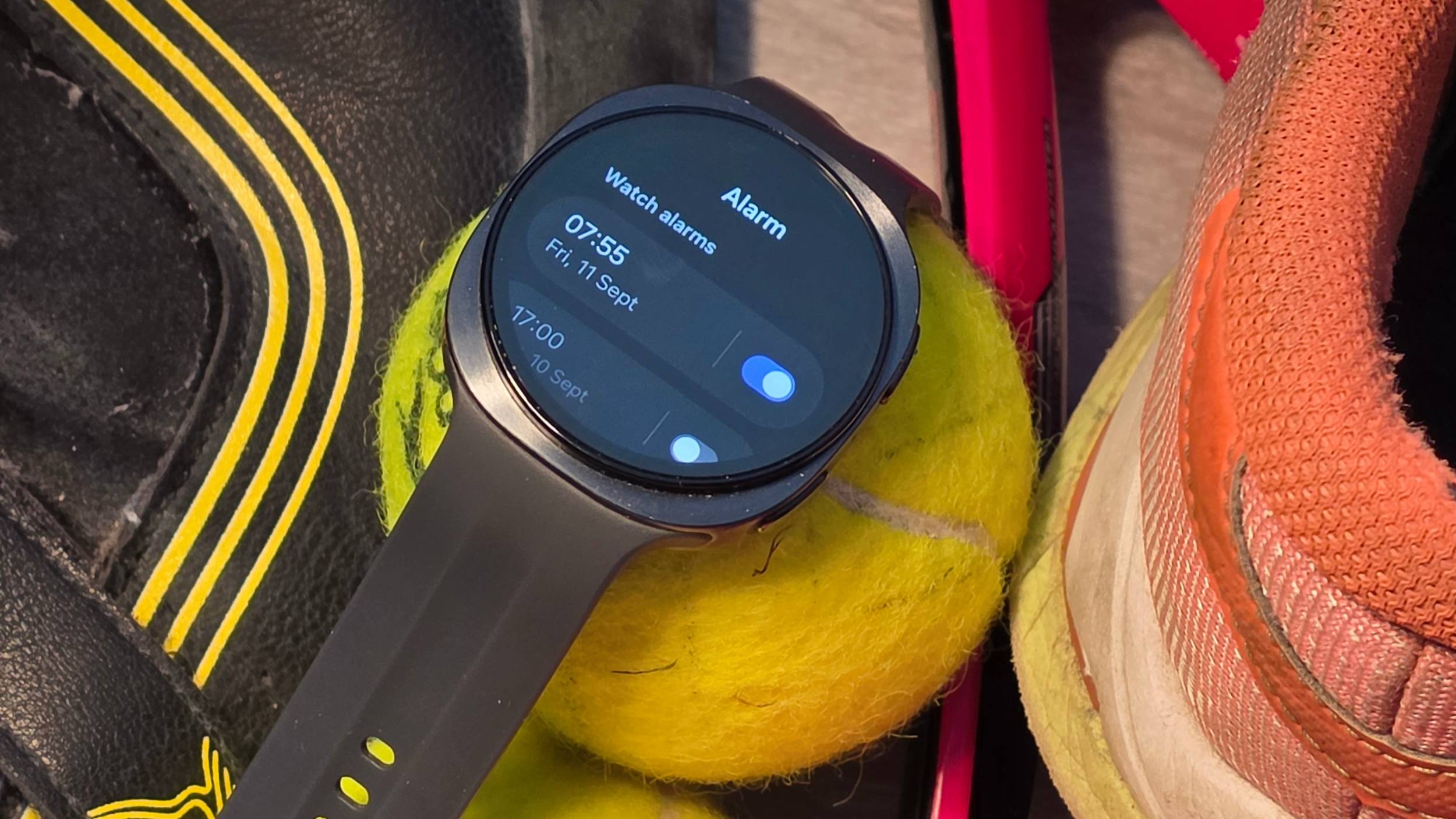 The Samsung Galaxy Watch 9 on a tennis ball, showing an alarm.
