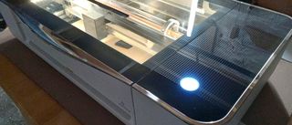 Glowforge Pro review is represented by a photo of a laser cutter on a table, it's lights are on