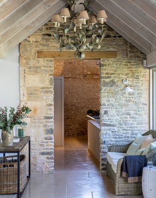 Rustic hallway with stone wall wooden console table and metal chandelier
