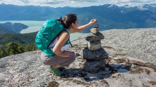Woman stacking rocks on mountain summit