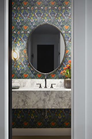 Colorful bathroom by Jeffrey Neve with patterned wallpaper and marble sink