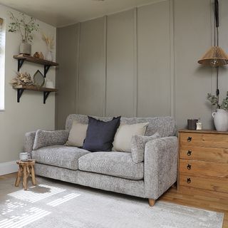 A greige-painted living room with wooden accents and a grey sofa