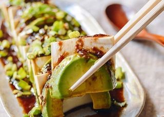 chopsticks picking up a piece of tofu and avocado