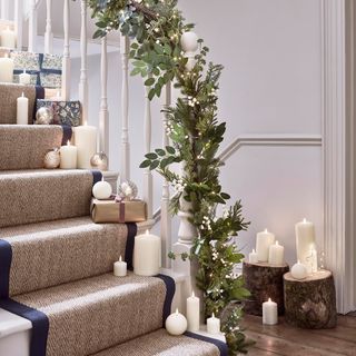 Christmas decorated hallway with garland on bannister and faux candles up the stairs