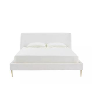 A white upholstered bed with gold legs