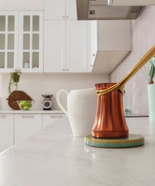 An image of white marble countertop with white wooden kitchen cabinets in the background