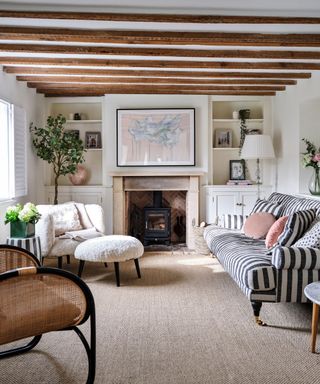 Blue and white stripped sofa, white armchair and footstool, stone fireplace