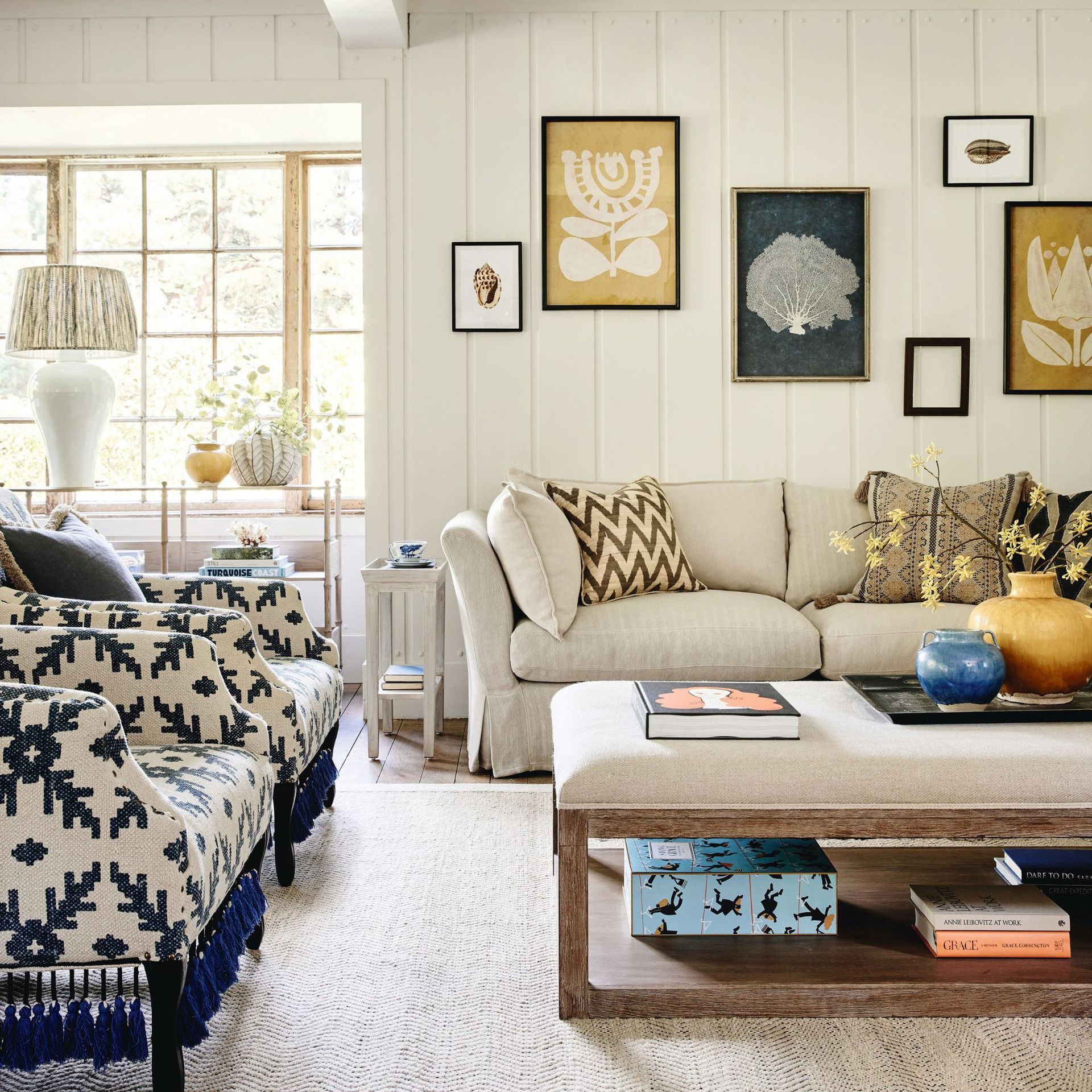 gallery wall with yellow and grey theme in living room with neutral sofa and patterned armchairs