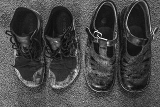 two pairs of scuffed and worn out school shoes