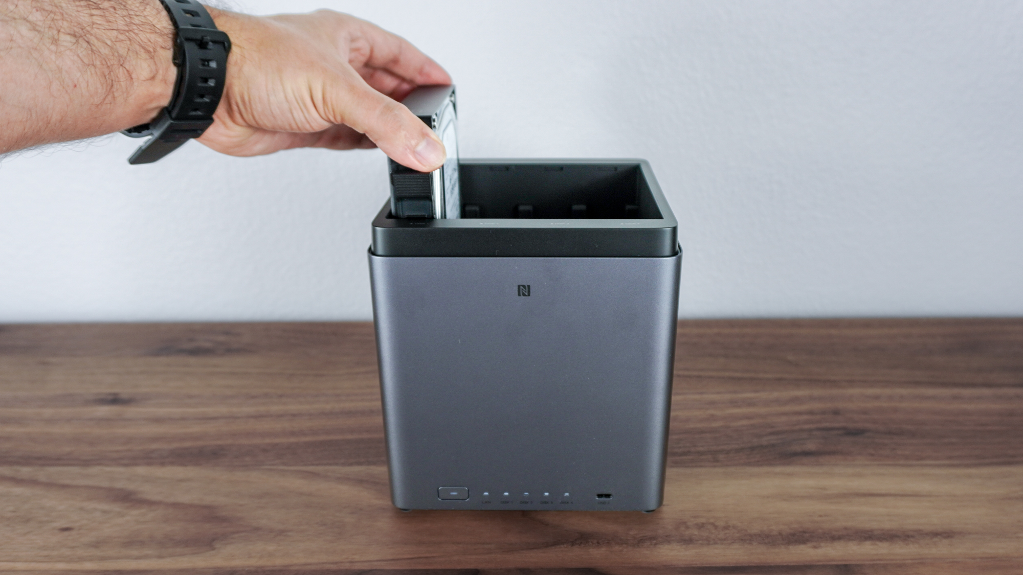 A person inserting a hard drive into the Ugreen NASync DH4300 Plus