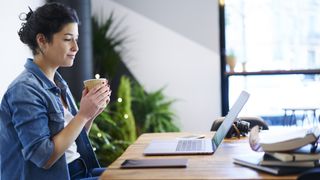 En student som ser på YouTube-video i et bibliotek mens hun drikker en kopp kaffe.