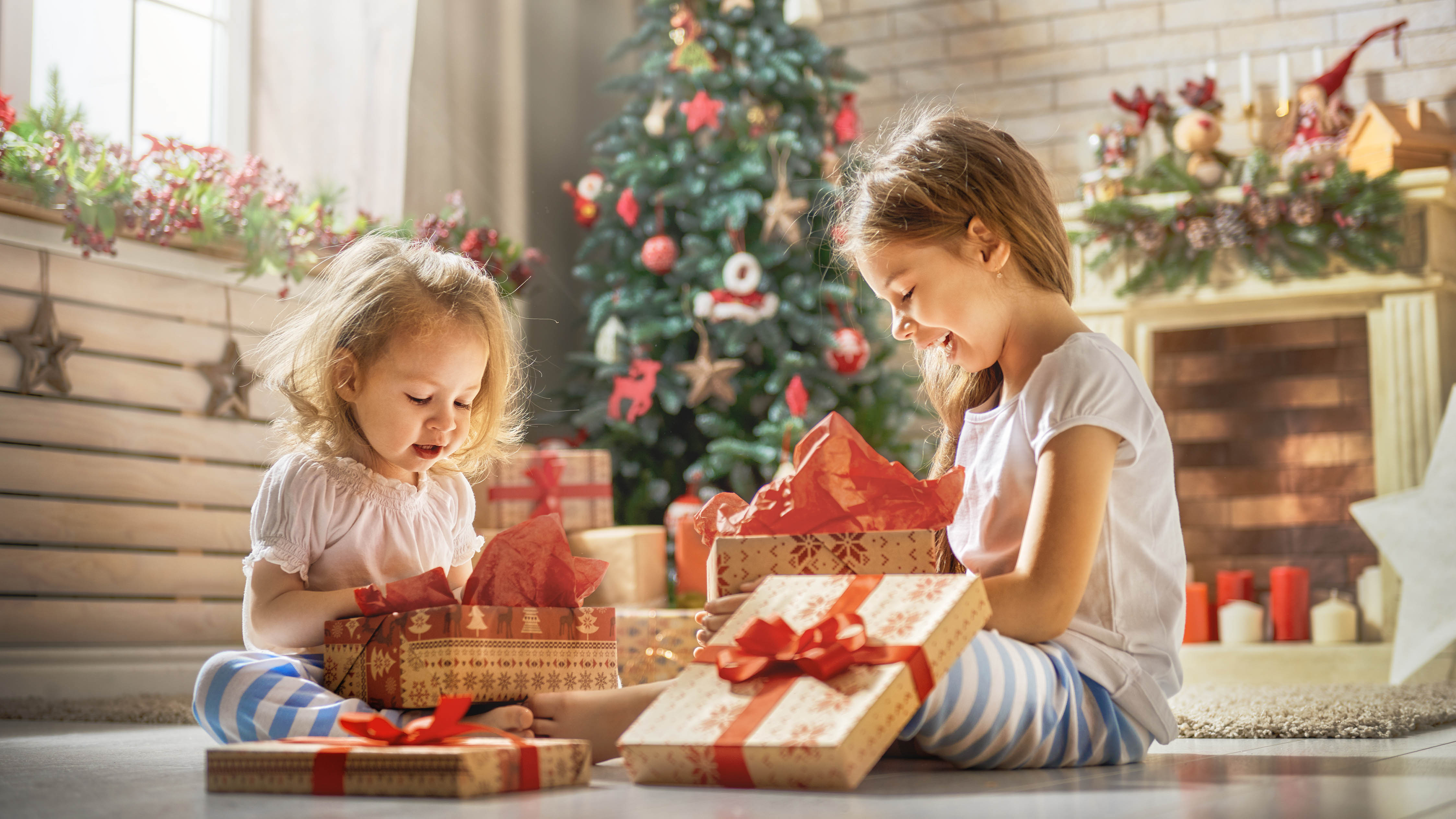 Двое детей открывают подарки на Рождество