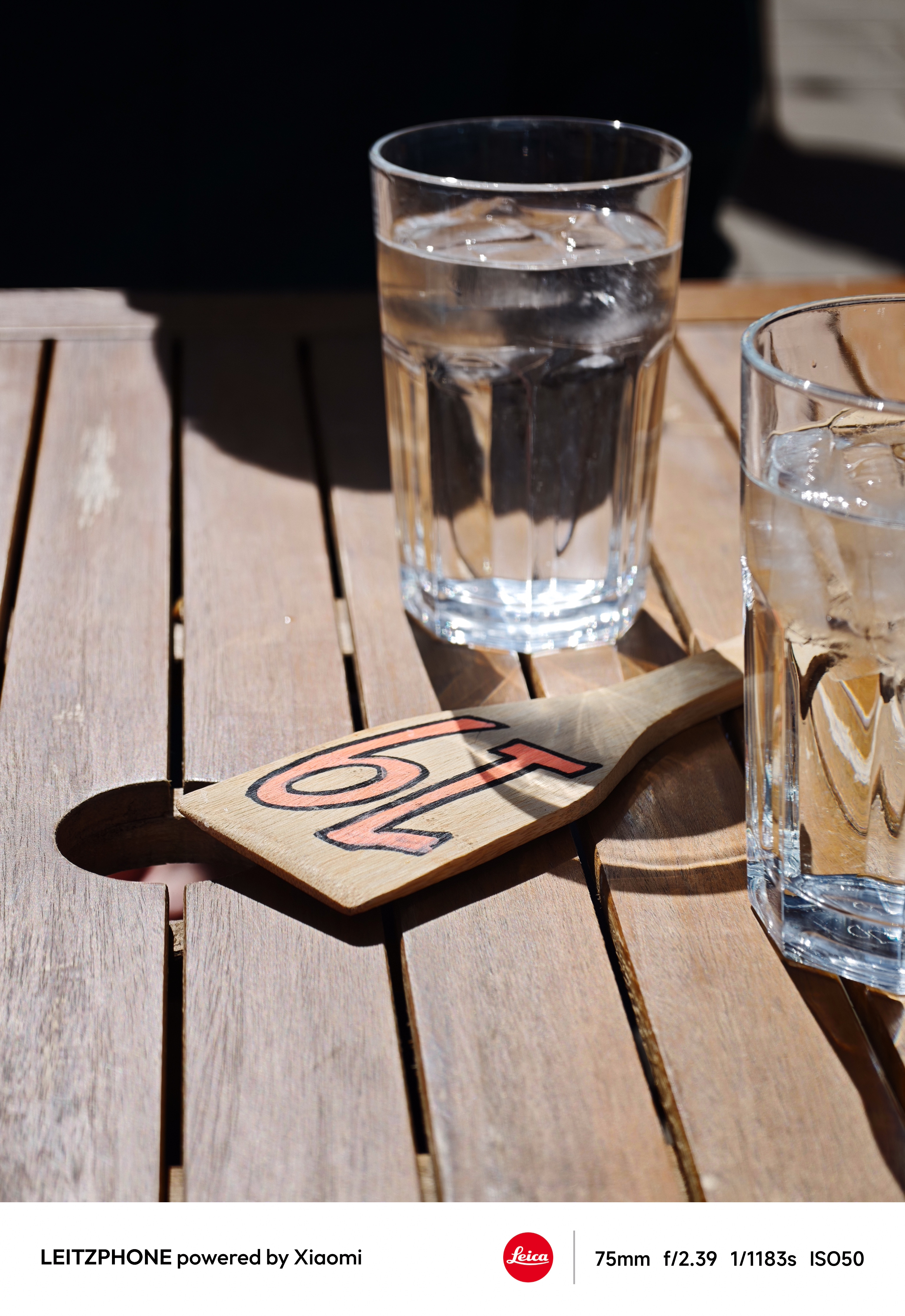 Glasses of iced water and table number on a wooden table