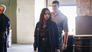 Lala looking down at her CI being treated by paramedics while Gibbs stands behind her in NCIS: Origins