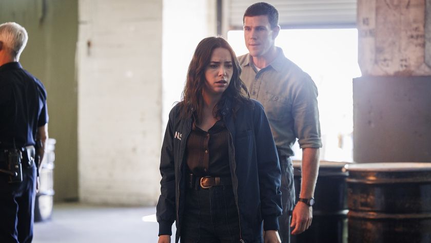 Lala looking down at her CI being treated by paramedics while Gibbs stands behind her in NCIS: Origins