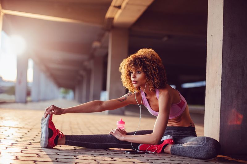 A female runner stretching on the floor outdoors