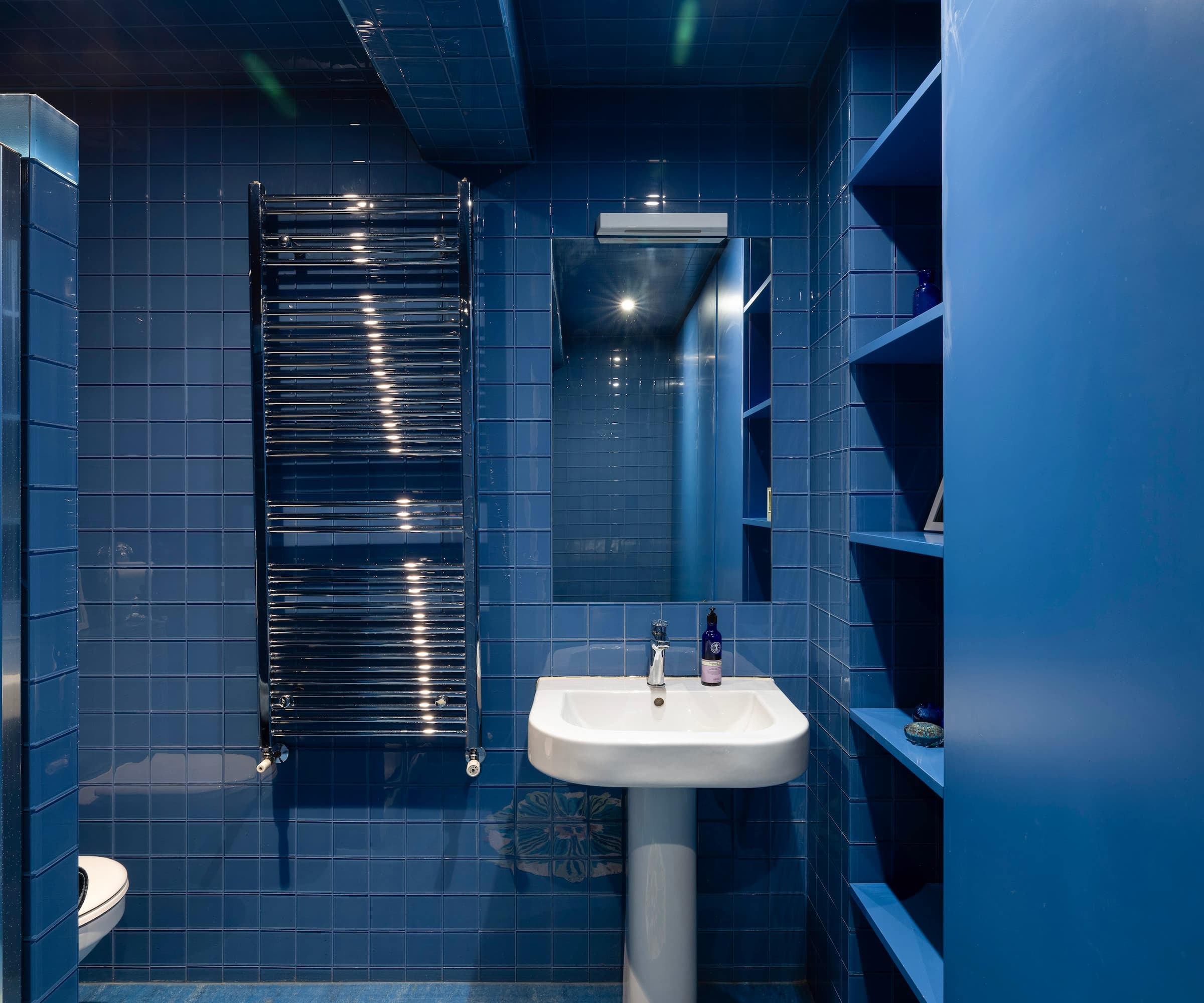 A completely blue tiled bathroom with a white sink