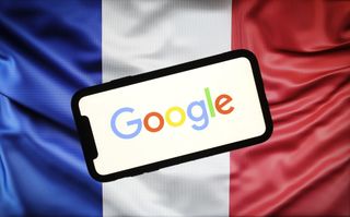 The Google logo displayed on a smartphone in front of a French flag