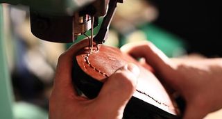 A shoe cobbler machining the sole of a brogue