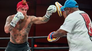 Jake Paul boxing his sparring partner while wearing a rooster wig