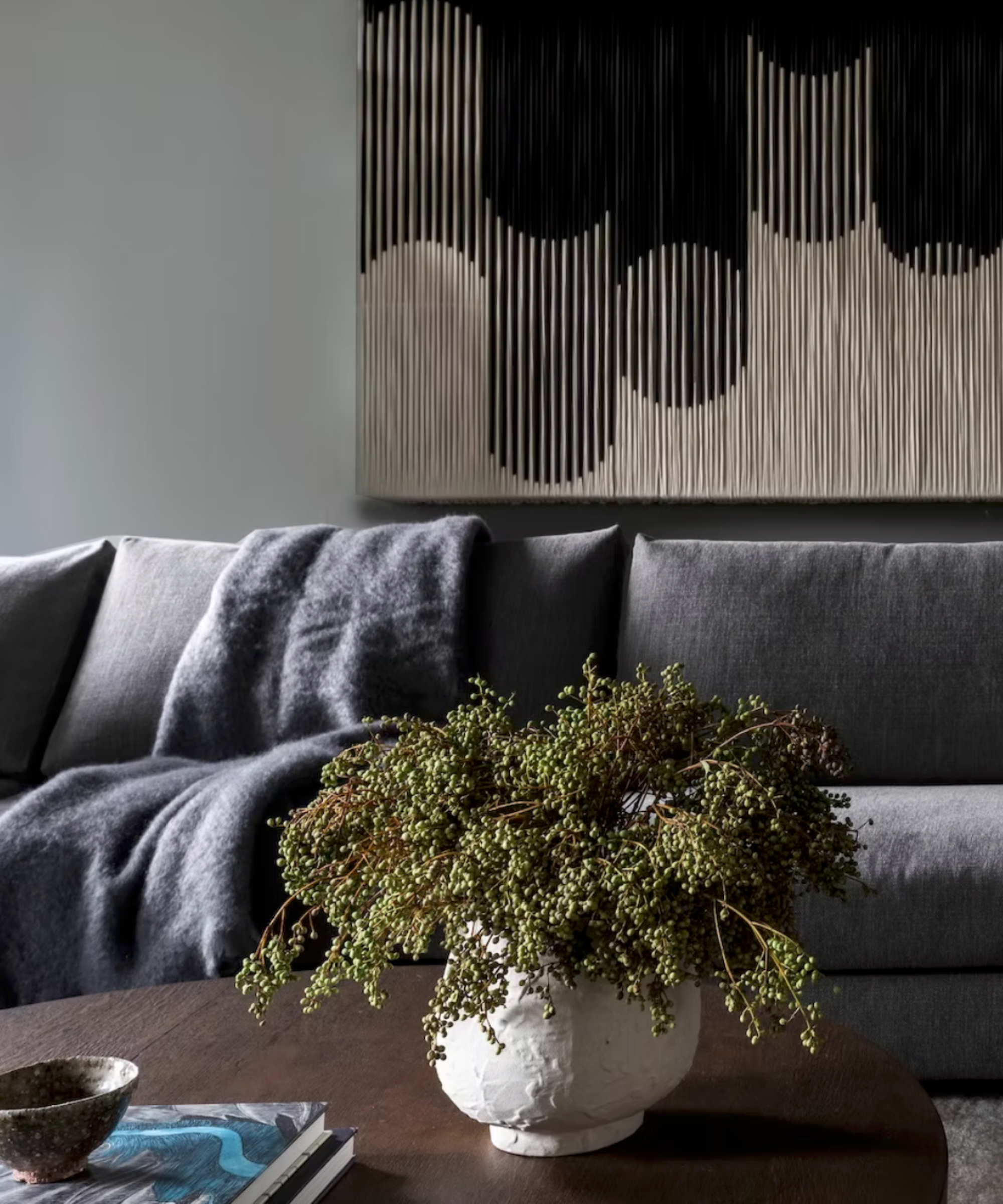 Moody grey sofa in dark living room with green floral arrangement on coffee table