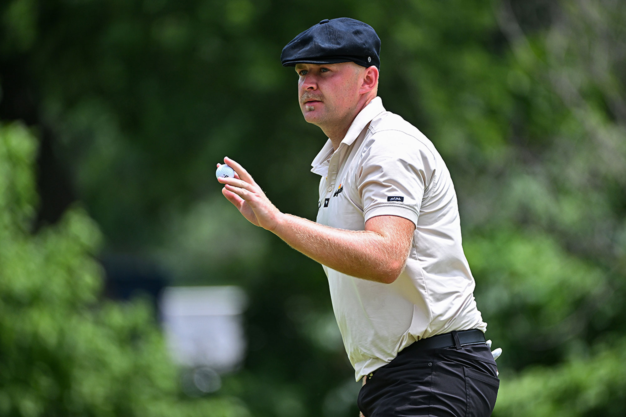 Harry Hall thanking the crowd for their applause by holding the golf ball up in gratitude after making a birdie