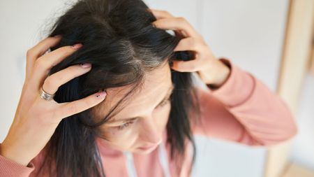 woman inspecting grey heads along her hairline