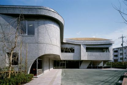 Contemporary building with patterned curving concrete walls and an overhanging first storey.