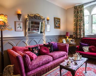 snug with grey gothic wall paneling and red and pink sofas and table set for afternoon tea