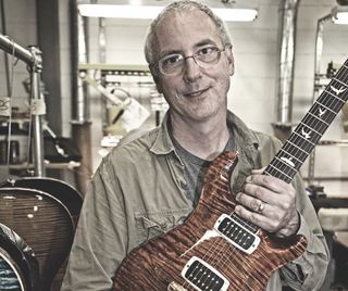 Paul Reed Smith holds a PRS guitar
