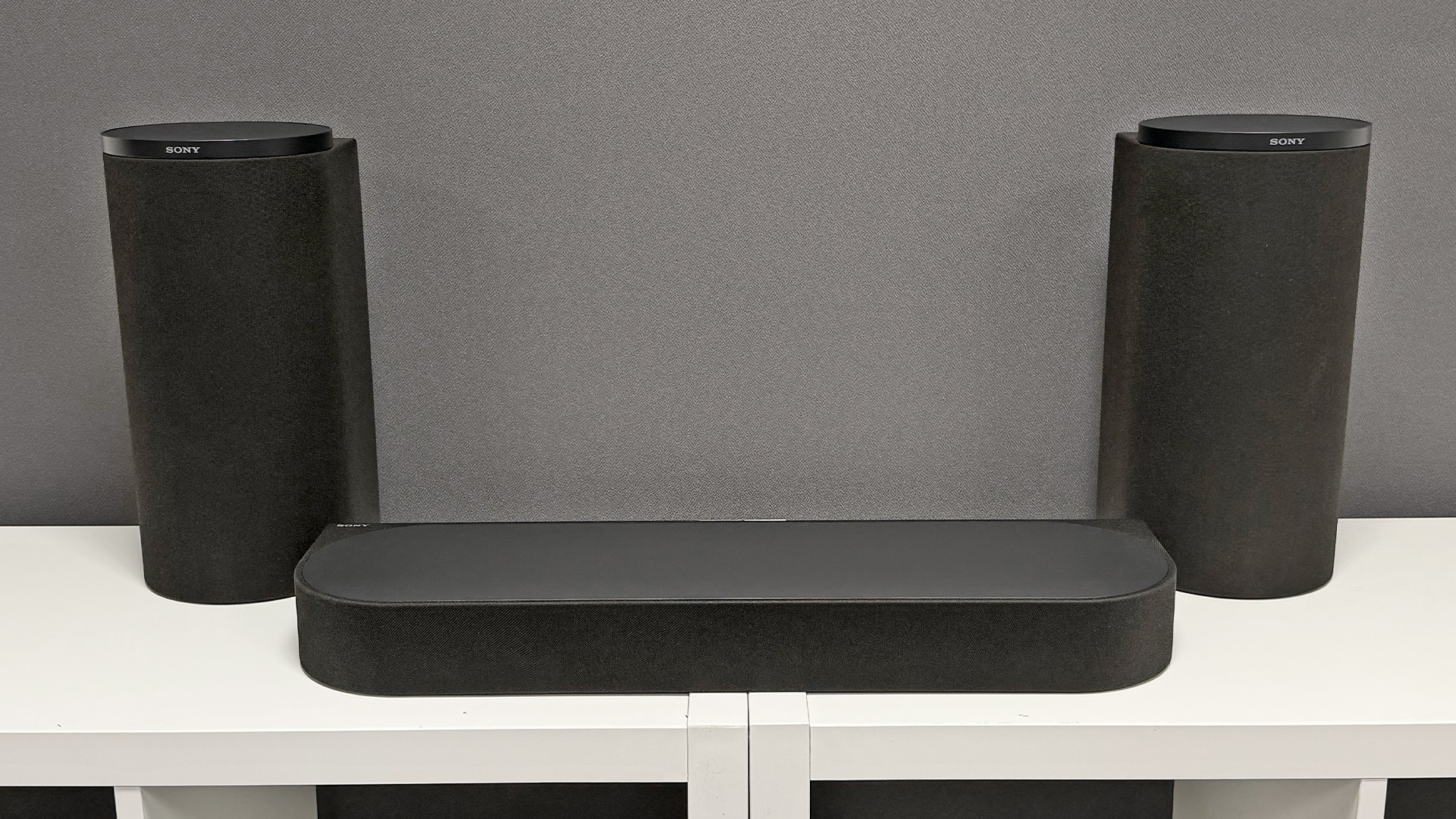 Sony Bravia Theatre Trio Dolby Atmos soundbar on white wooden shelving unit in front of grey wall