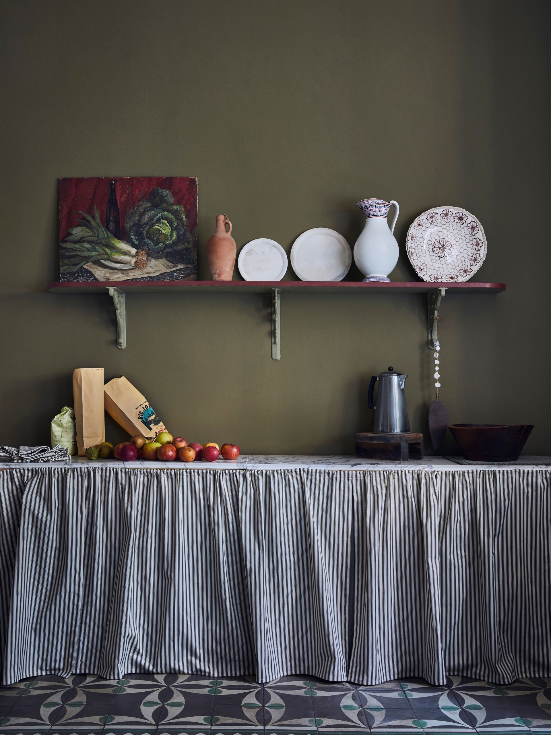 Olive green kitchen ideas featuring open wooden shelving, a striped curtain under the countertops and patterned tile flooring.