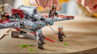 Hand playing with Star Wars Ahsoka Jedi Shuttle Lego set