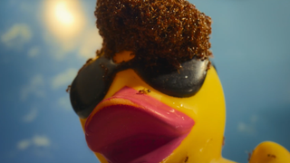 a yellow rubber duck with sunglasses with thousands of fire ants perched on its head