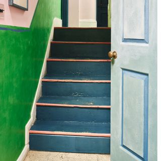 Hallway with painted front door, stairs and walls in different colours