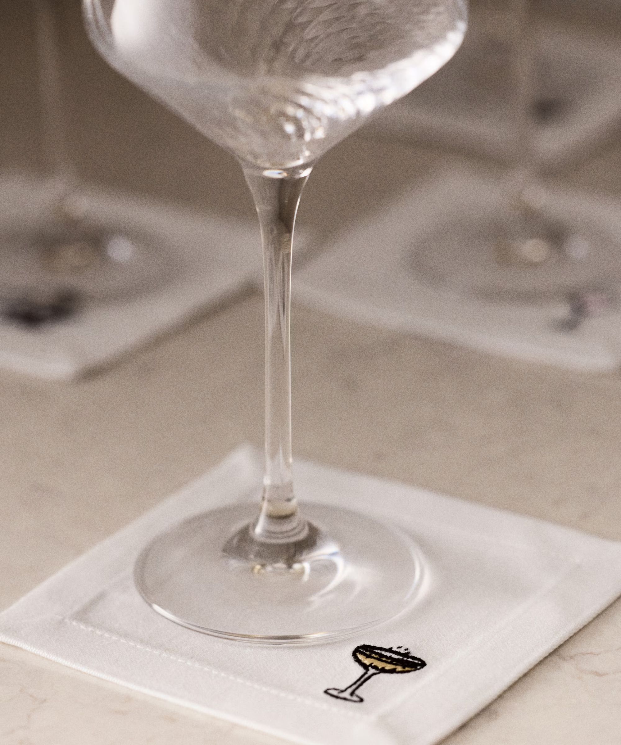 Coupe glass on white embroidered coaster