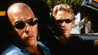 Vin Diesel as Dominic Toretto and Paul Walker as Brian O'Conner sitting in a car together during the movie The Fast and the Furious.