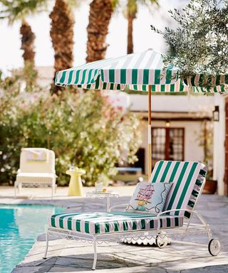 striped retro poolside patio lounger with striped upholstery and a matching green and pink striped umbrella