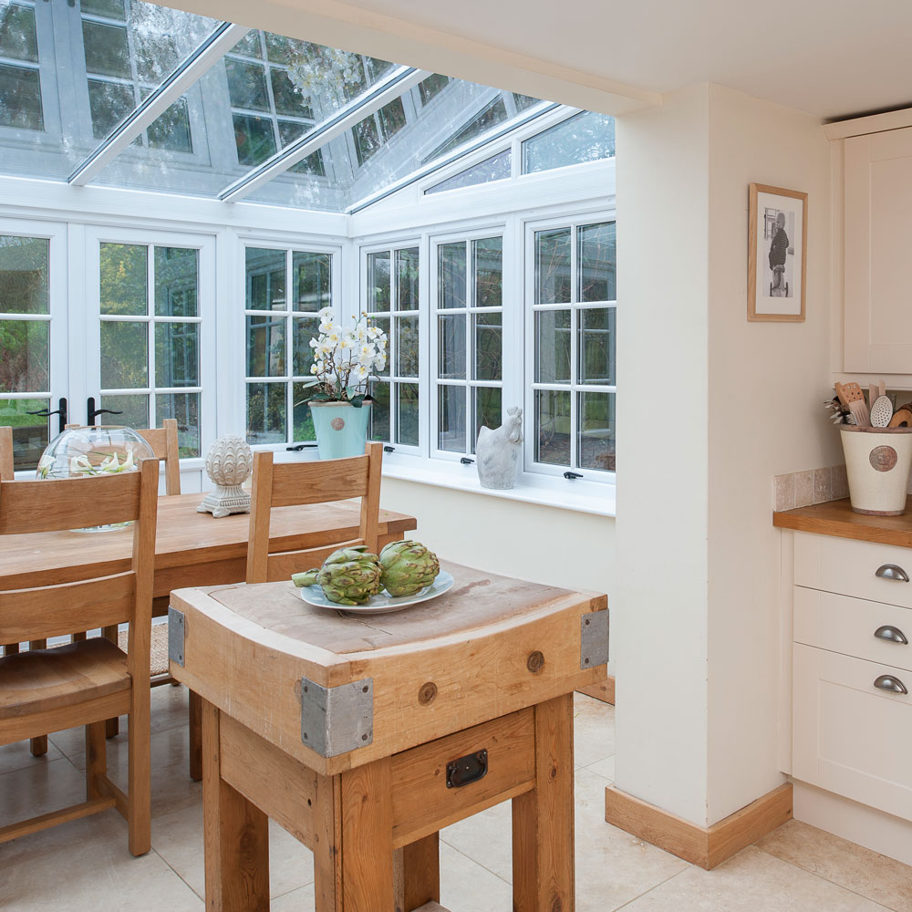 extended kitchen with glass roof and walls of windows and dinner table with chairs