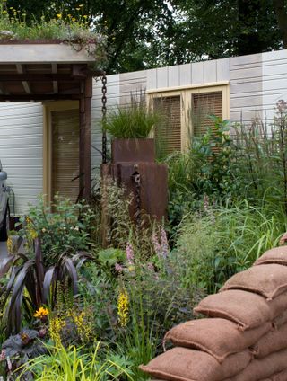 A rain garden with a a planted garage roof, a rain chain, and a sandbag wall