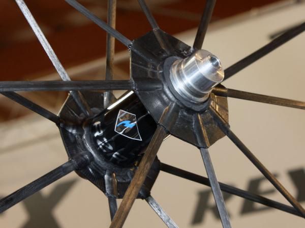 Save for the alloy axle ends and underlying bearings, everything else in this picture is carbon fiber from the airfoil-shaped spokes, the double-walled hub shell, both spoke flanges and even the central part of the axle.