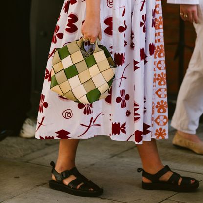 a woman at fashion week wearing black leather fisherman sandals