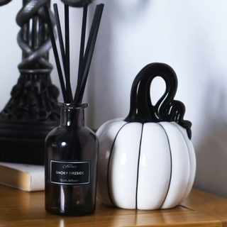 Halloween themed reed diffuser beside white ceramic pumpkin