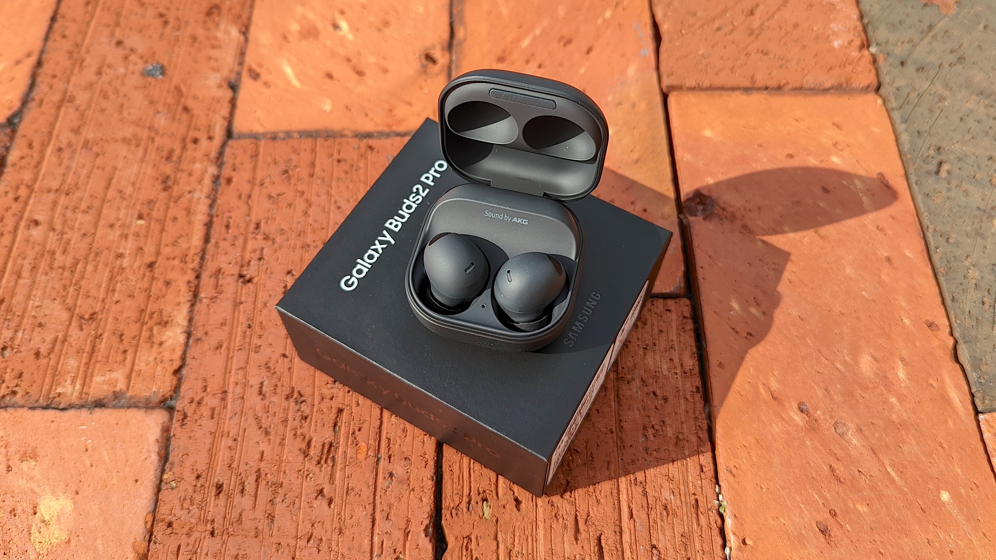The Samsung Galaxy Buds 2 Pro unboxed and displayed atop an exposed brick surface