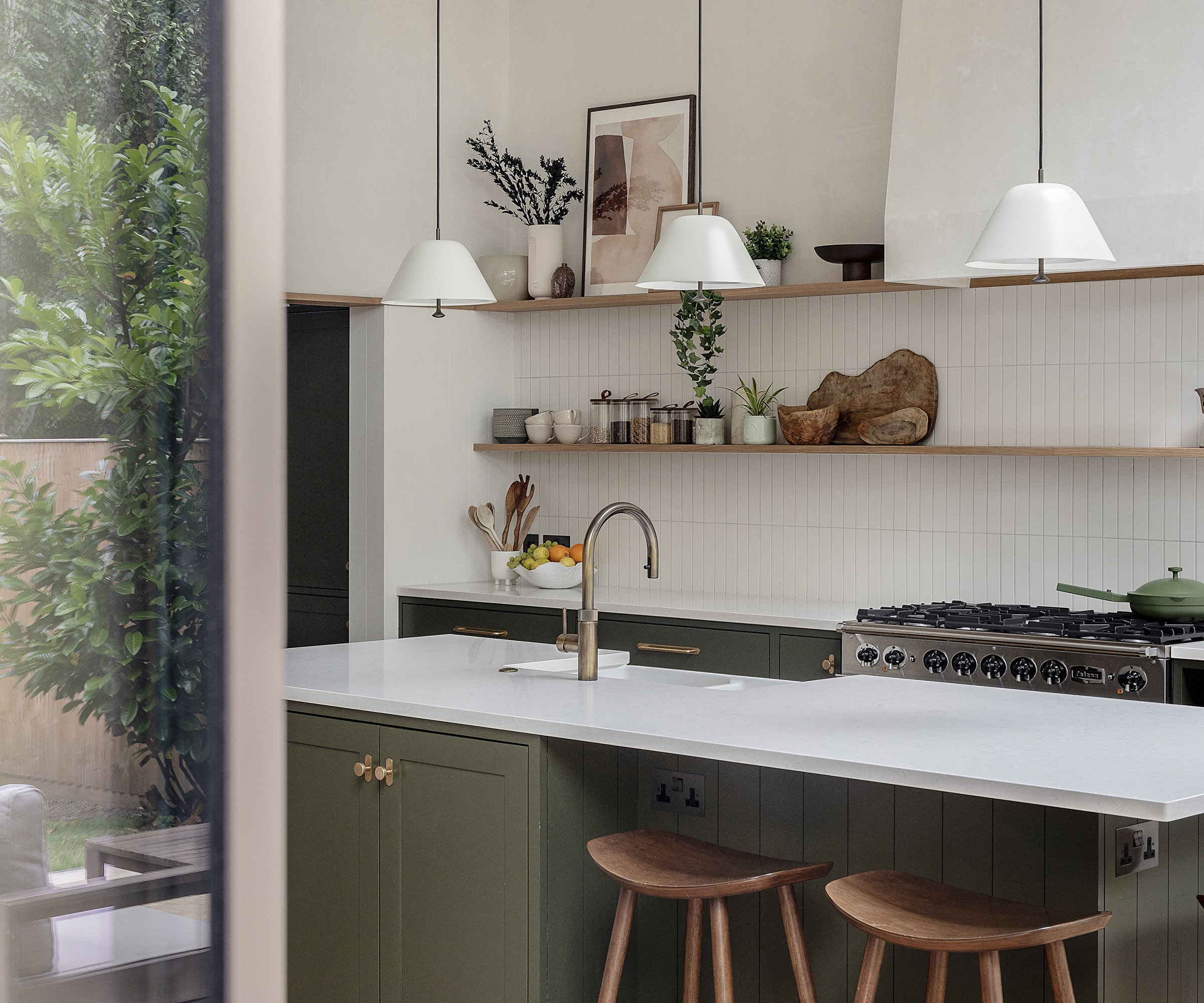 Dark khaki green kitchen cabinets with light surfaces and white tiled splashbacks