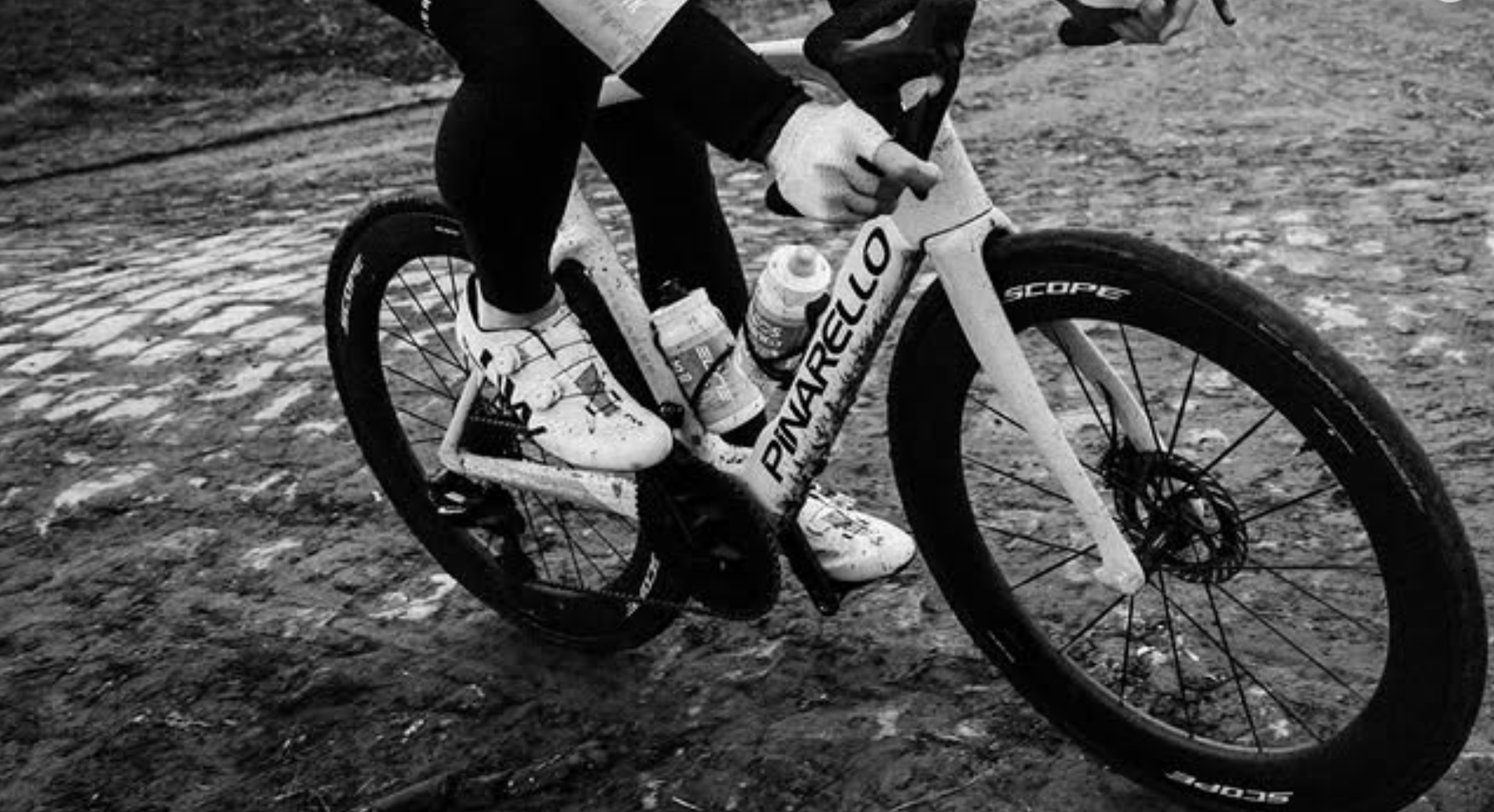 A black and white photo of a rider on cobbles