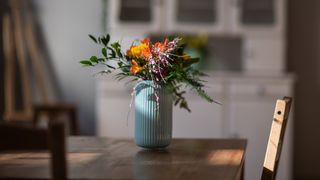 blue vase full of colorful flowers on a wooden table
