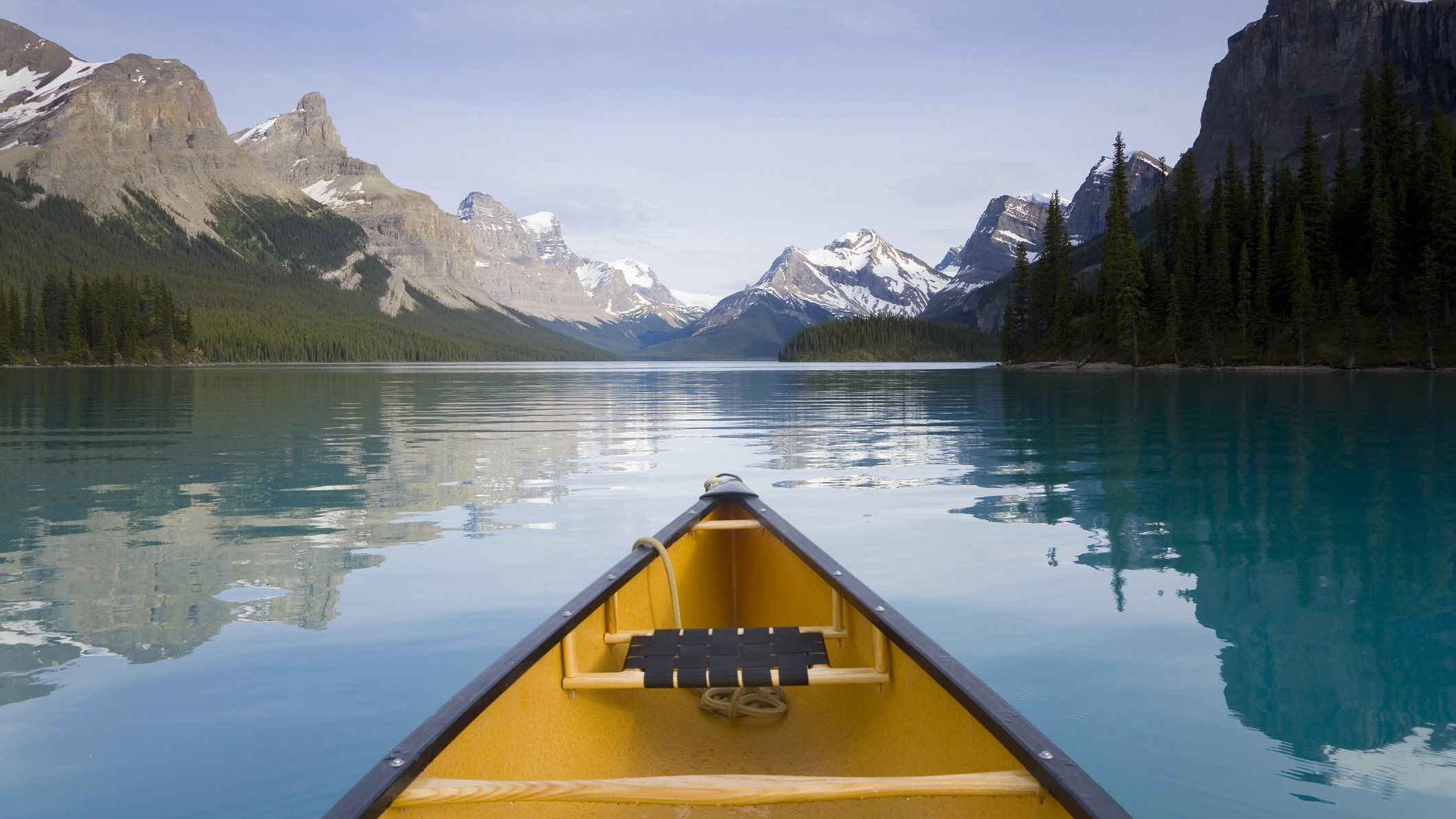 A yellow canoe sat on a calm lake with blue skies above