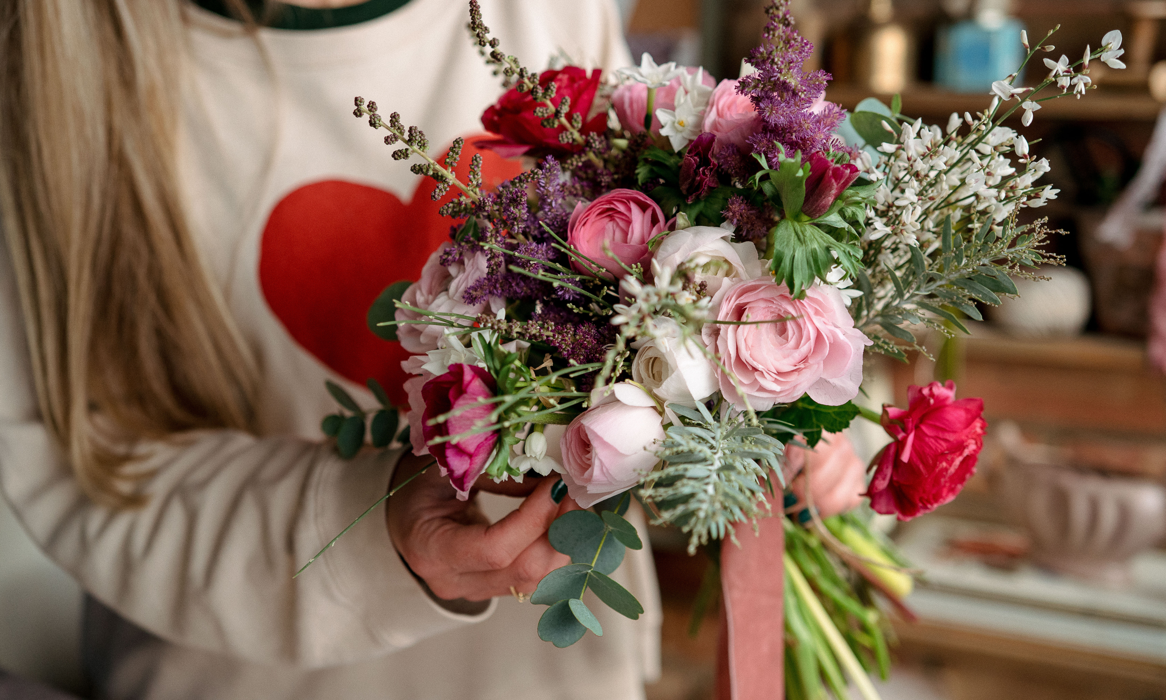 Hands holding a pink, green and purple hand-tied bouquet